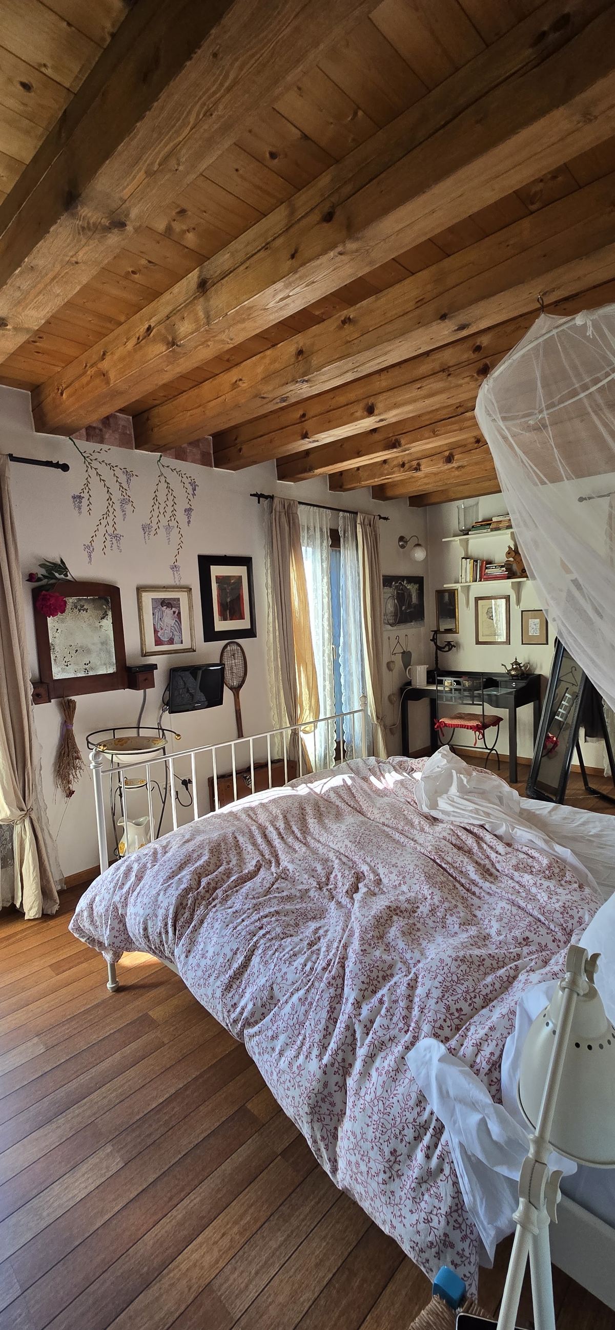 Camera mansardata con travi e piumone a fiori