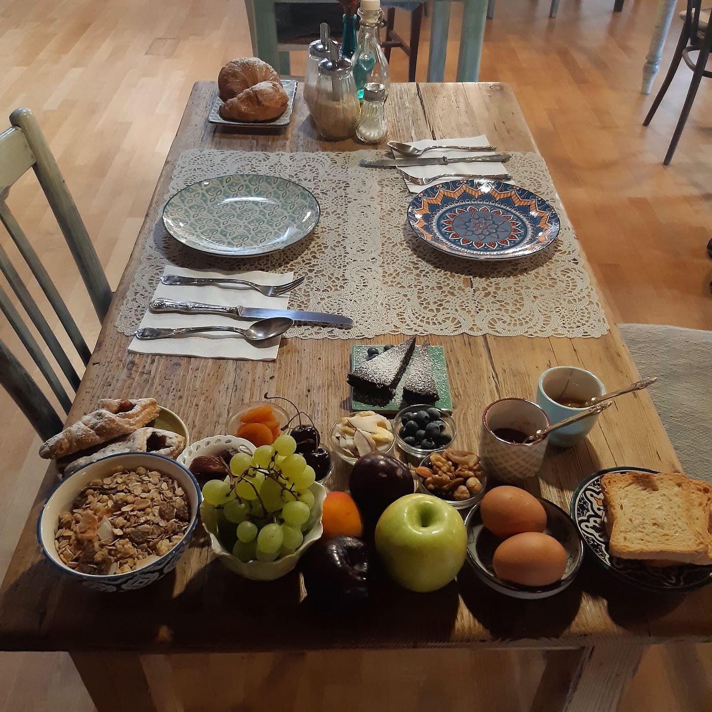 Tavola della colazione con frutta, uova, croissant, cereali e pane tostato